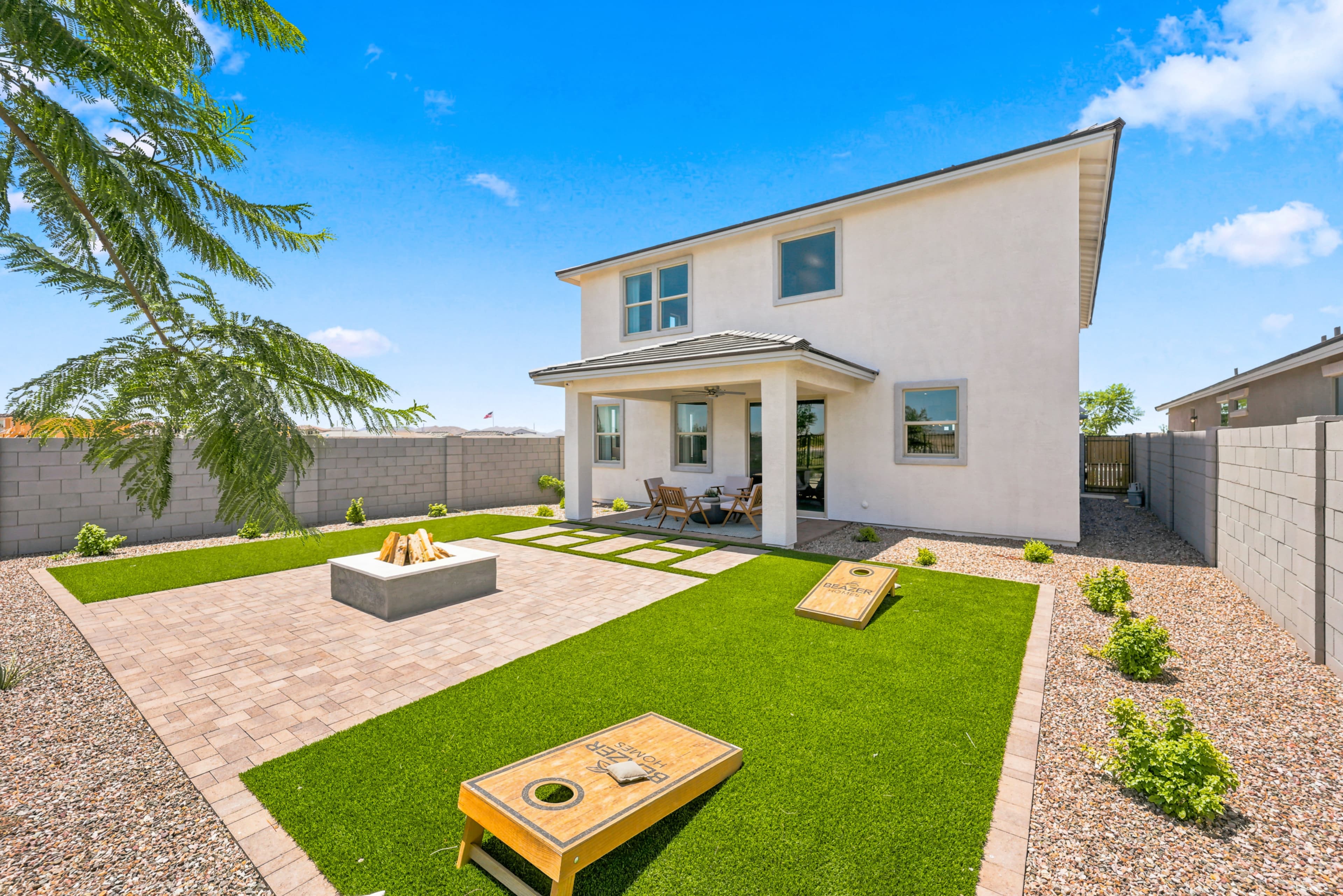spacious backyard with artificial turf, pavers, and a center fire pit for hosting gatherings