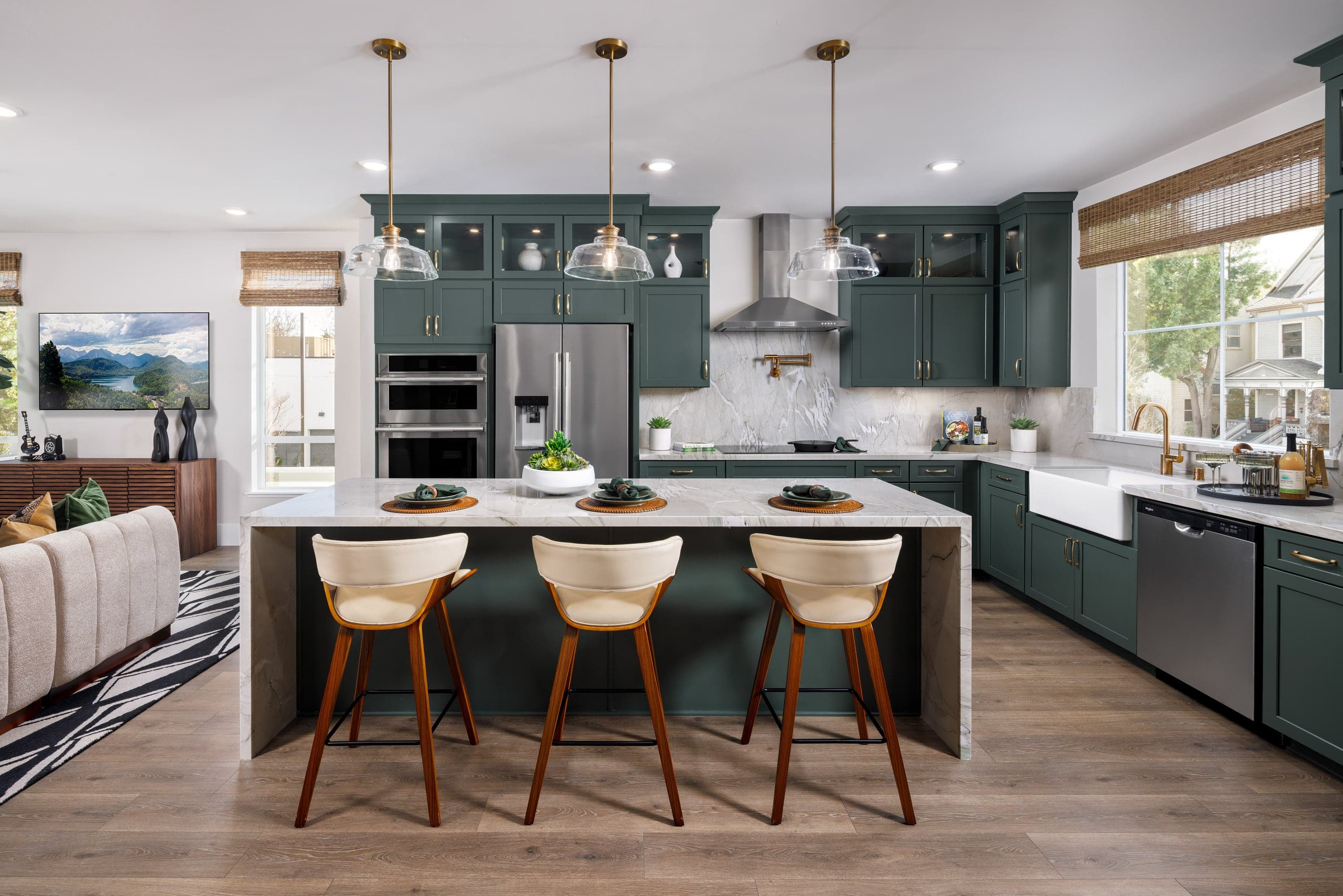 kitchen with green cabinets, quartz waterfall edge island, wood floors, and large window above sink