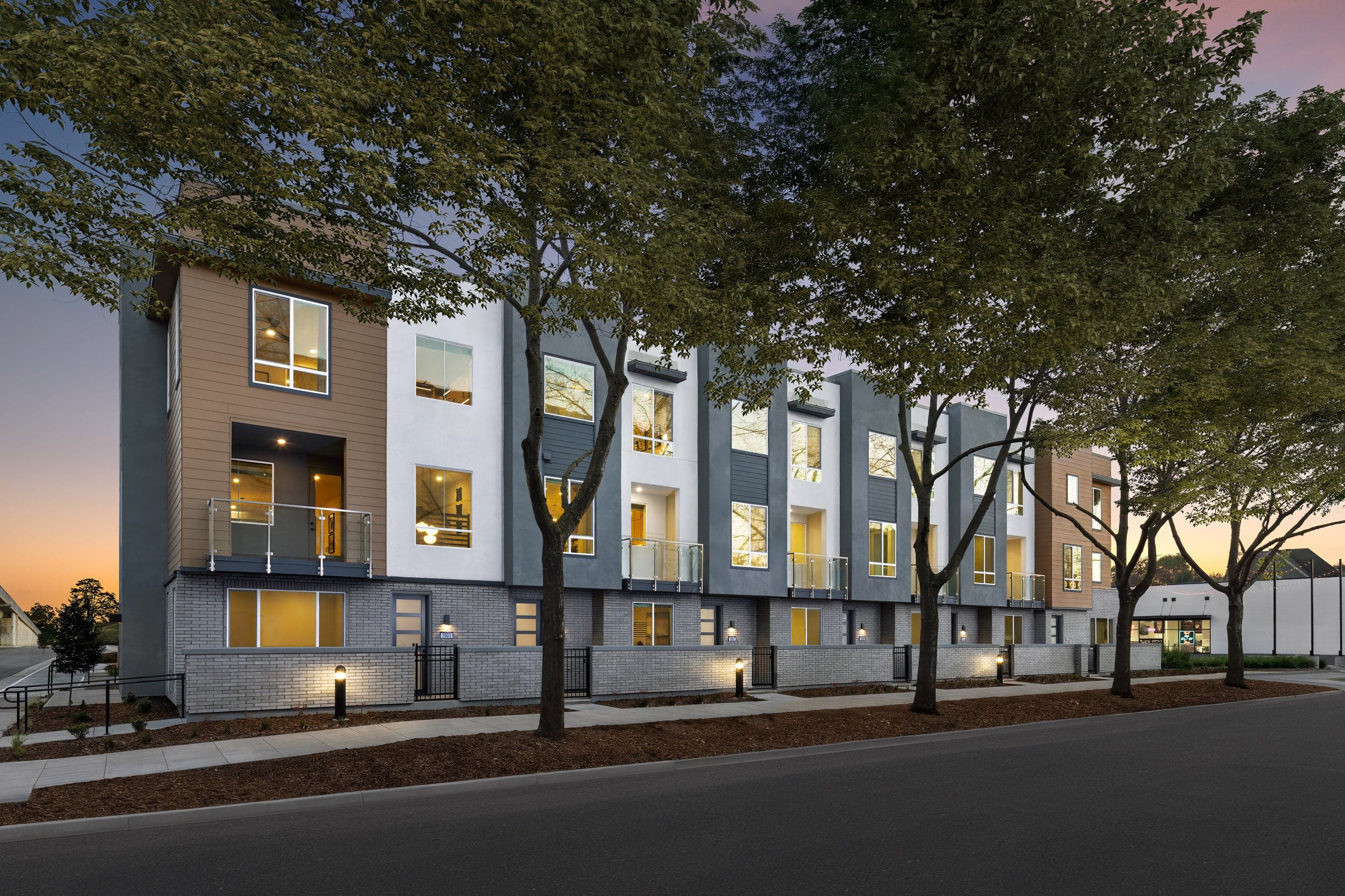 front exterior of brown, white, and gray condo building with courtyards and balconies