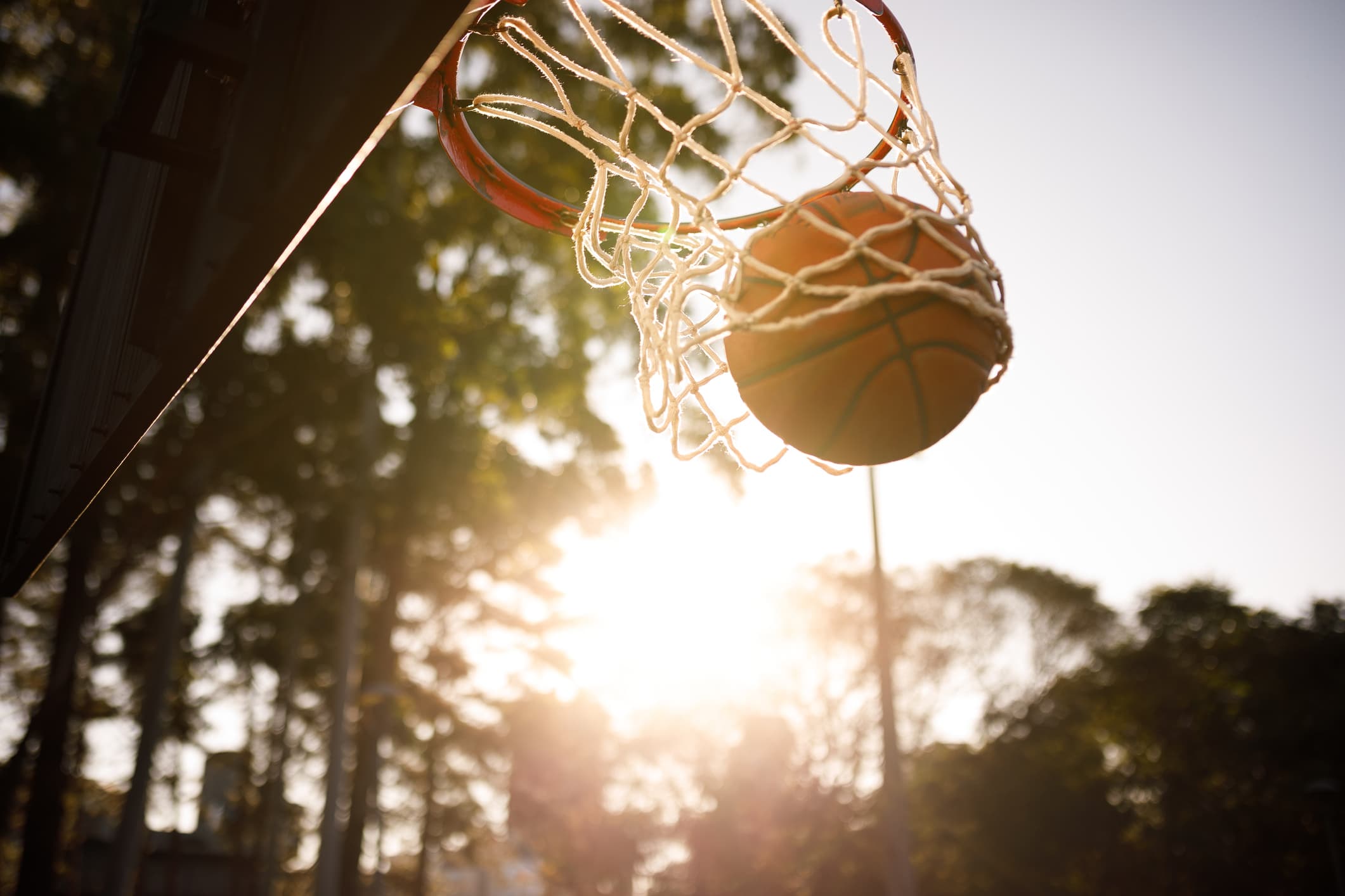 basketball being scored with the sun in the background
