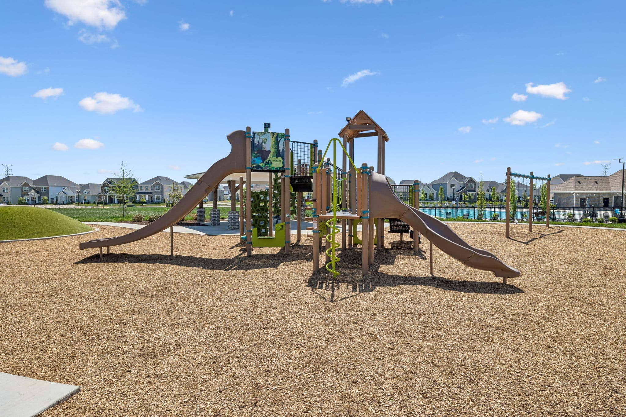 large playground with swings and slide beside pool 