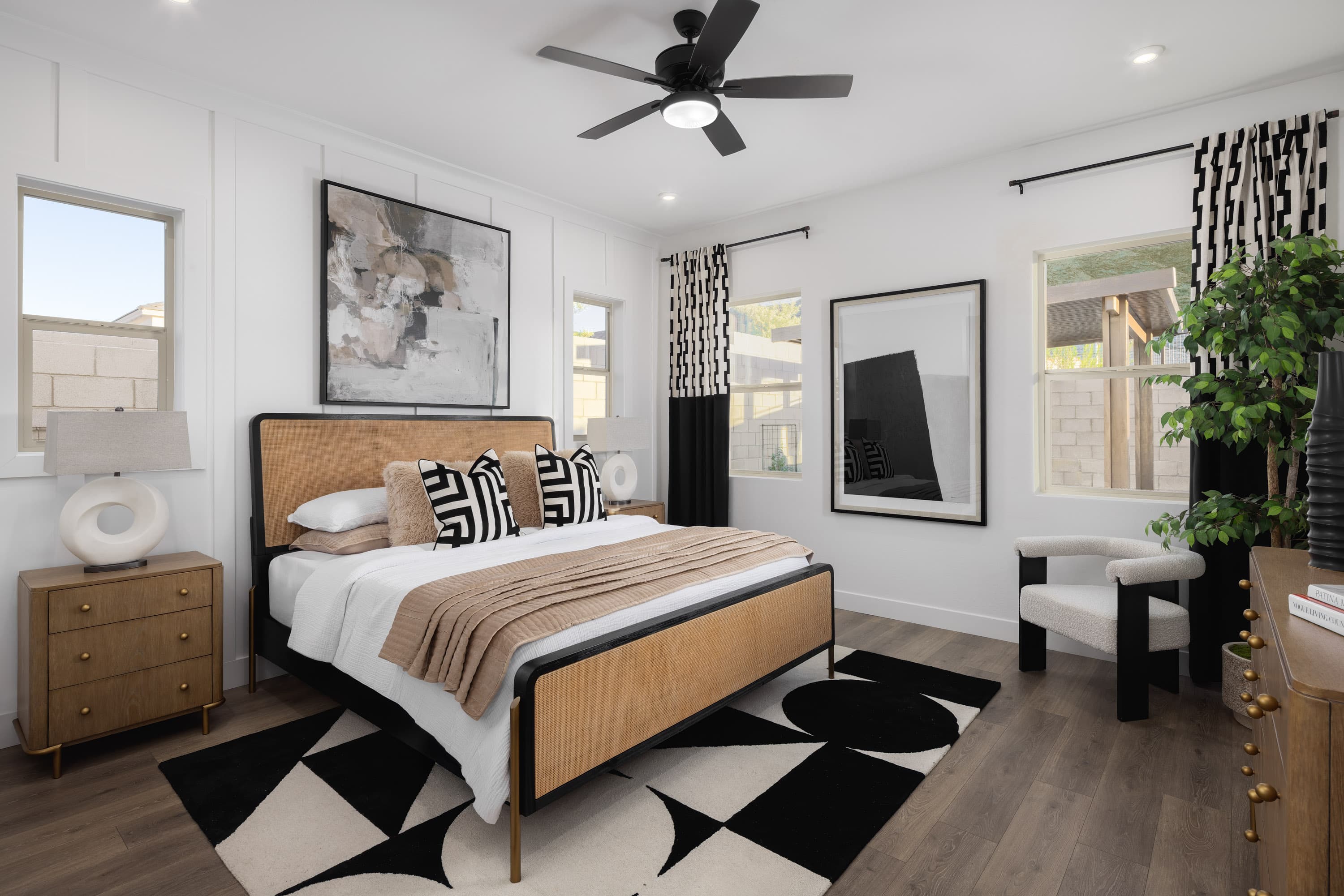 spacious bedroom with a large white bed, white accent chair, and wooden dresser
