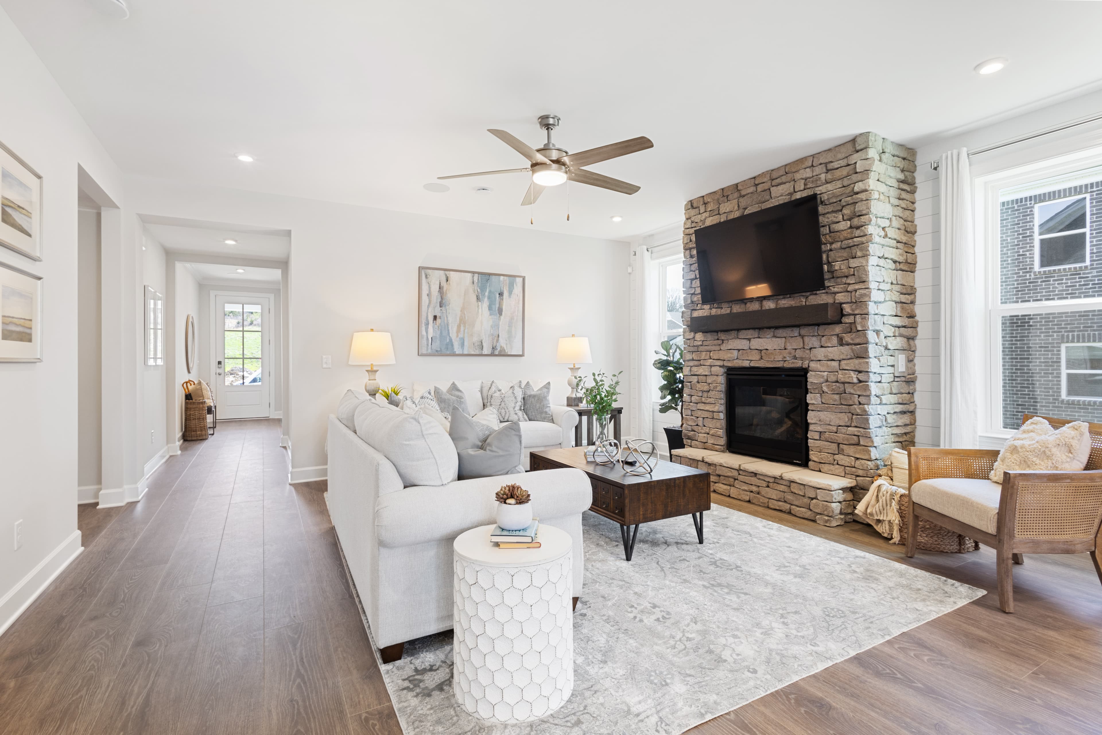 great room with wood floors, large windows, and stone fireplace