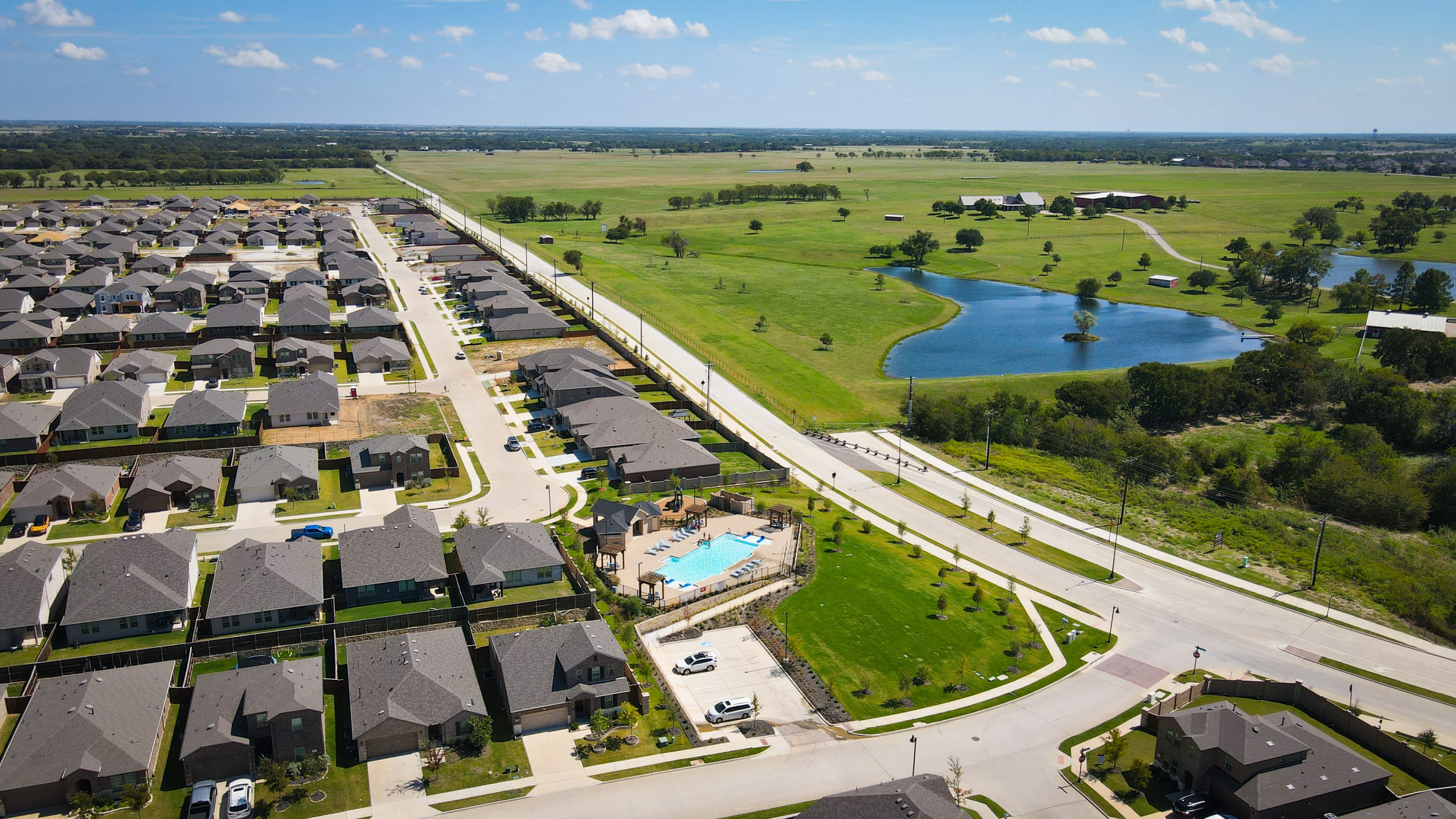 aerial of community with pool, pond, and green space