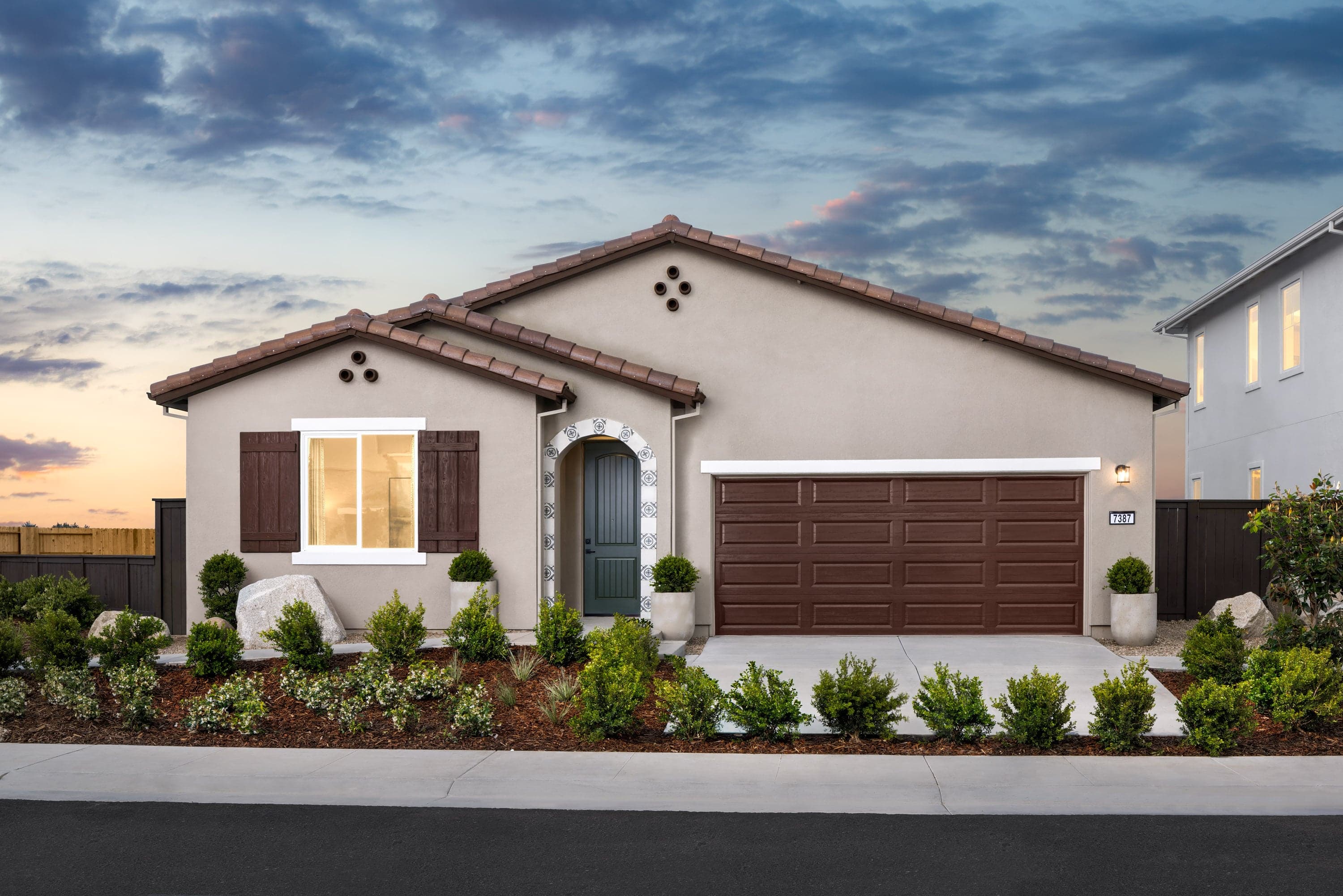front exterior of tan and brown single-story spanish style home at dusk