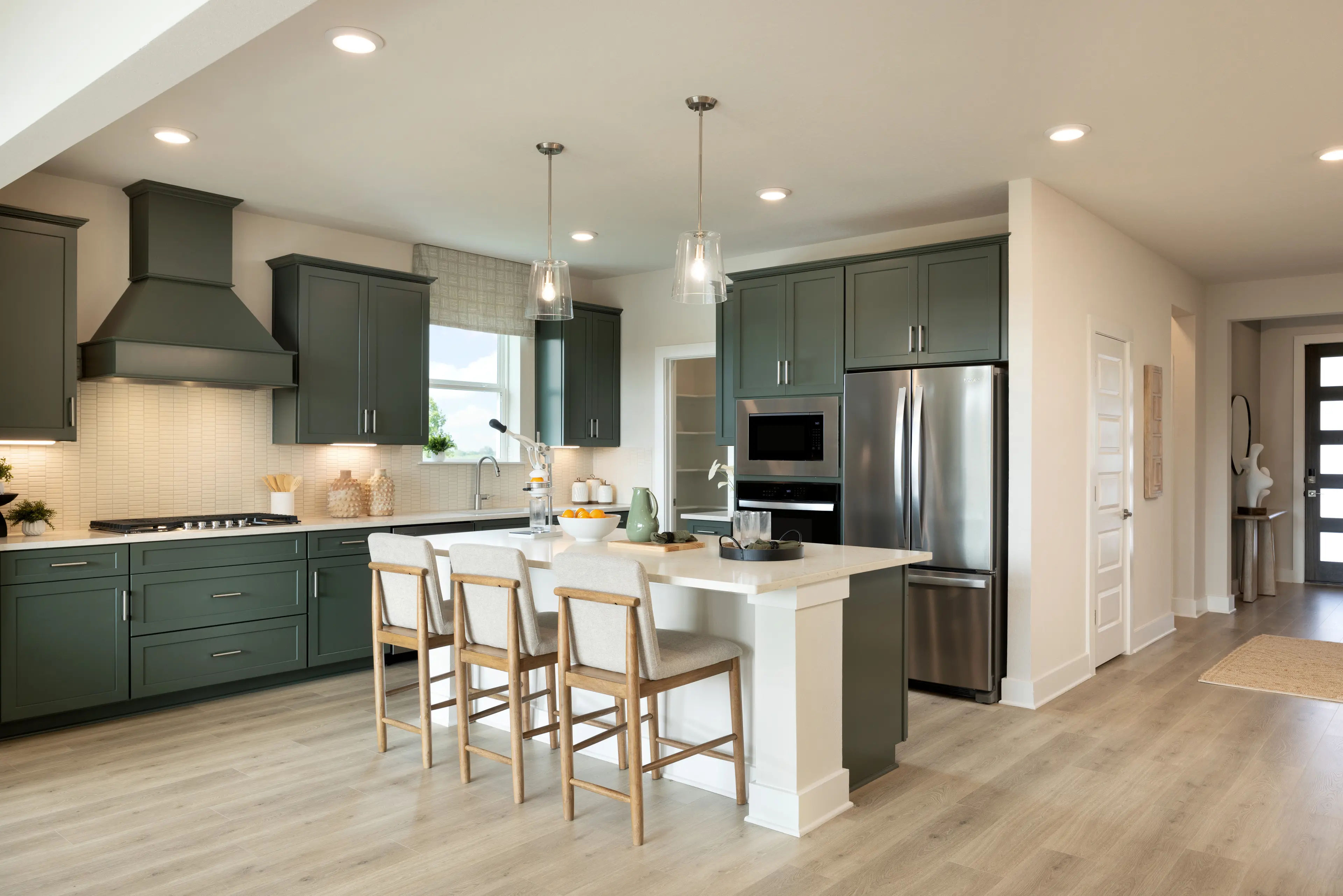 kitchen with hunter green cabinets, quartz countertops and pendant lighting