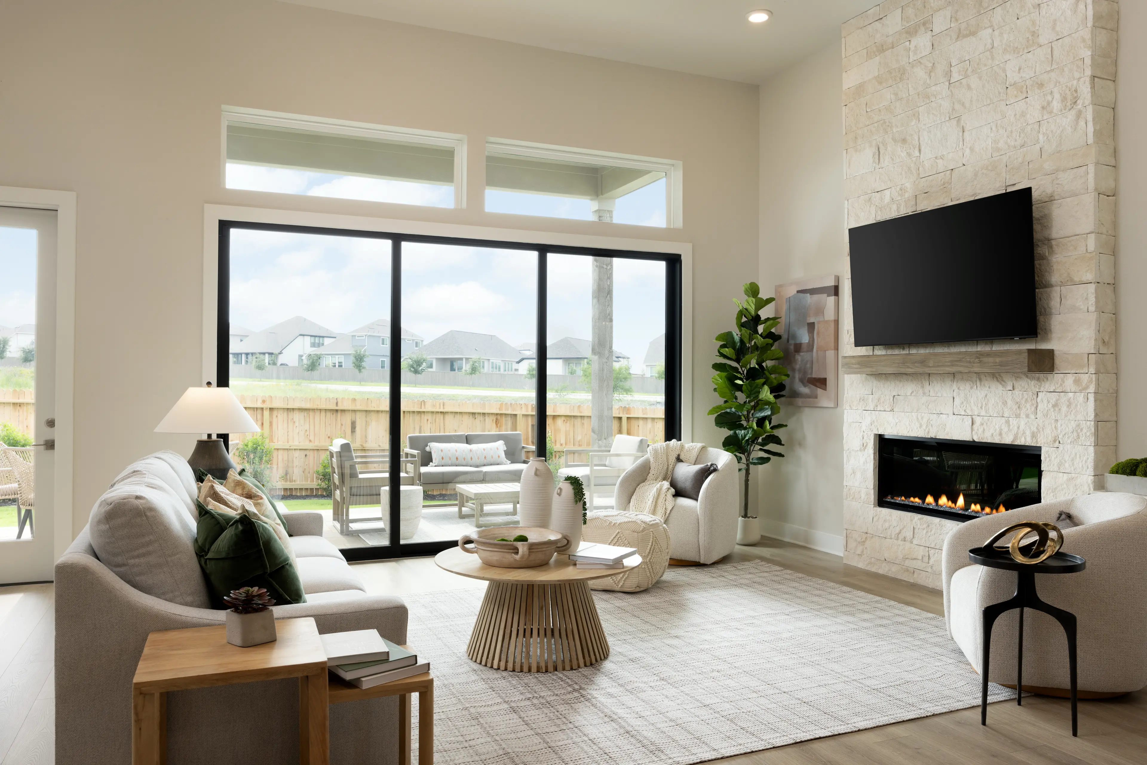 great room with brown flooring, windows and ceiling fan