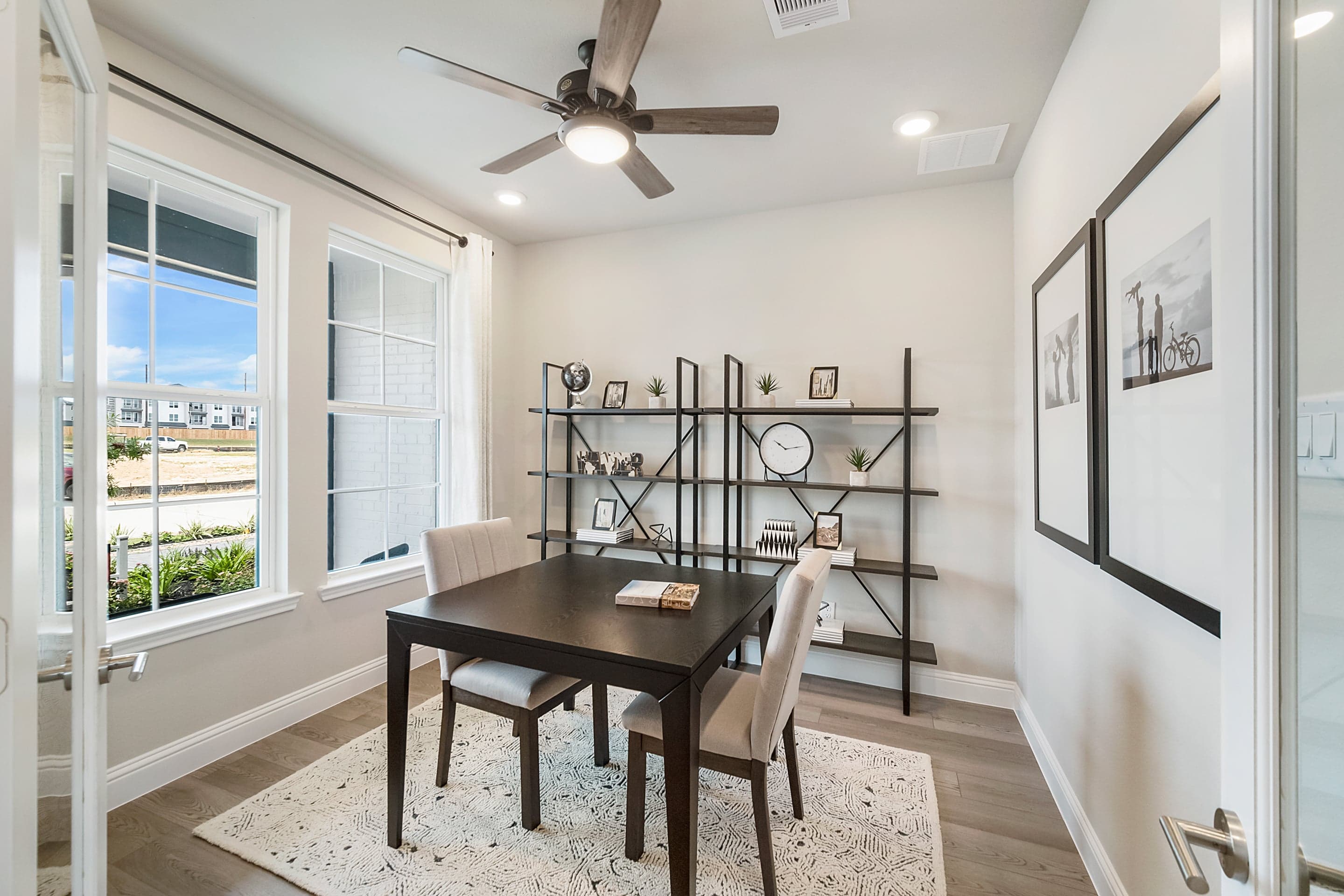 study with hardwood flooring and large windows