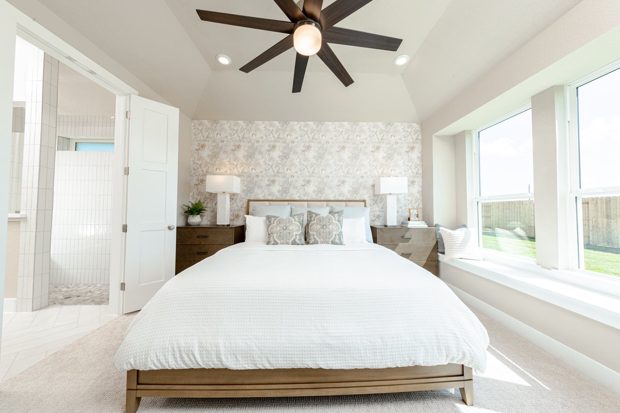 large primary bedroom with windows and tall ceilings