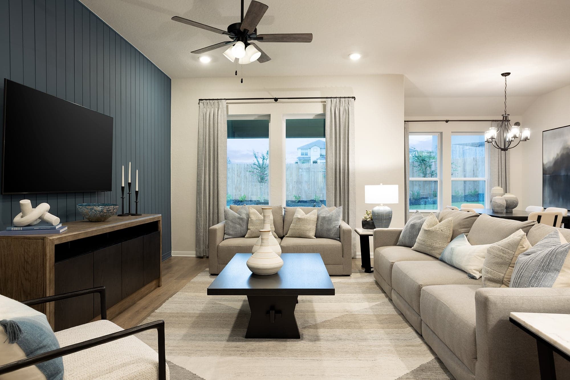 great room with brown flooring, windows and ceiling fan