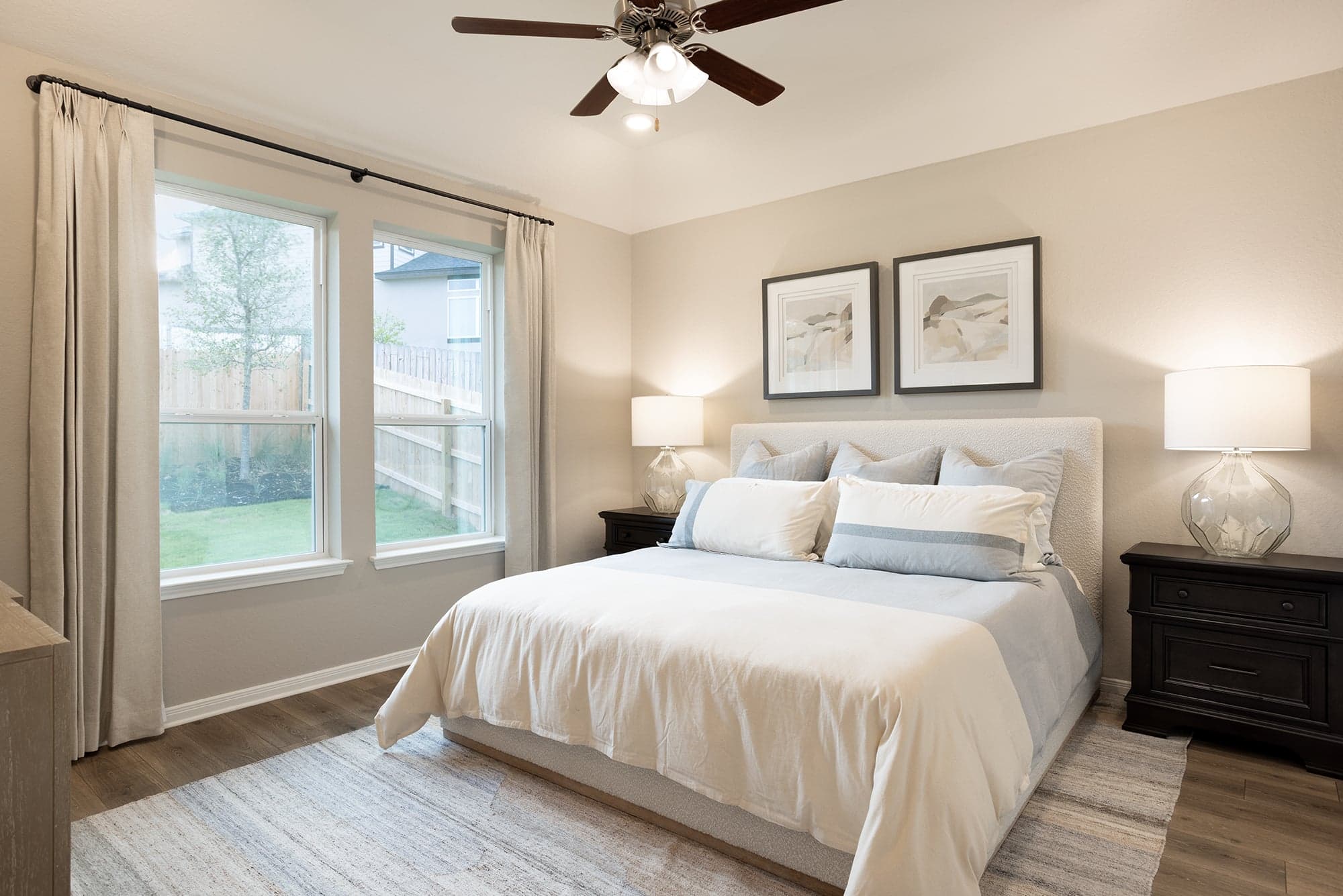 primary bedroom with brown floor, windows and a ceiling fan