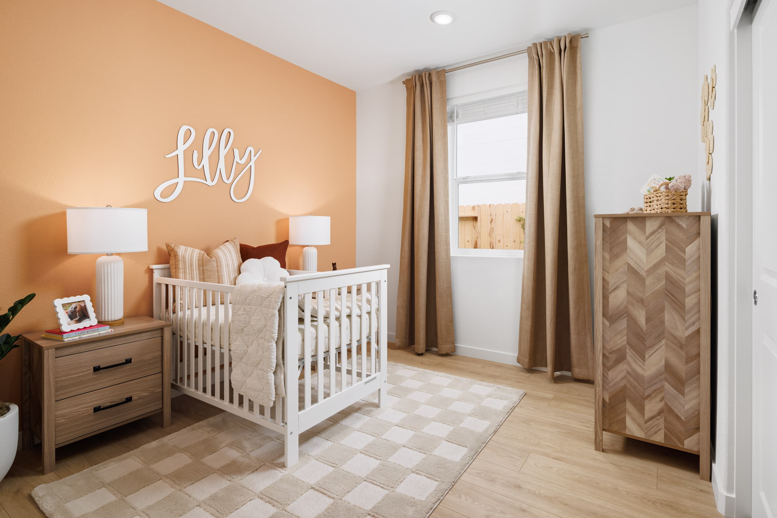 bedroom with wood floors, white crib, and brown fabric window panels