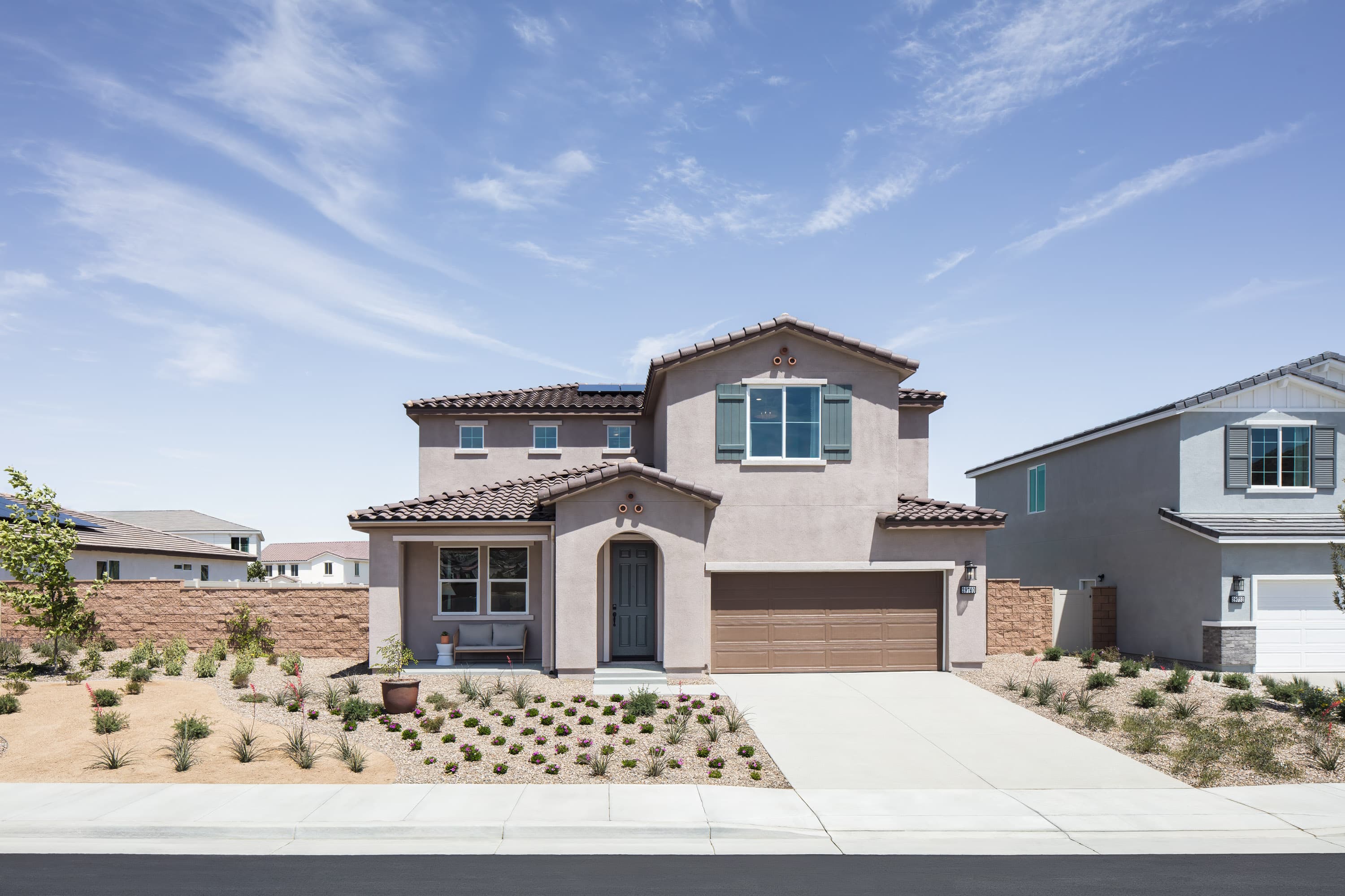 exterior of two-story home with brown garage and desert landscaping