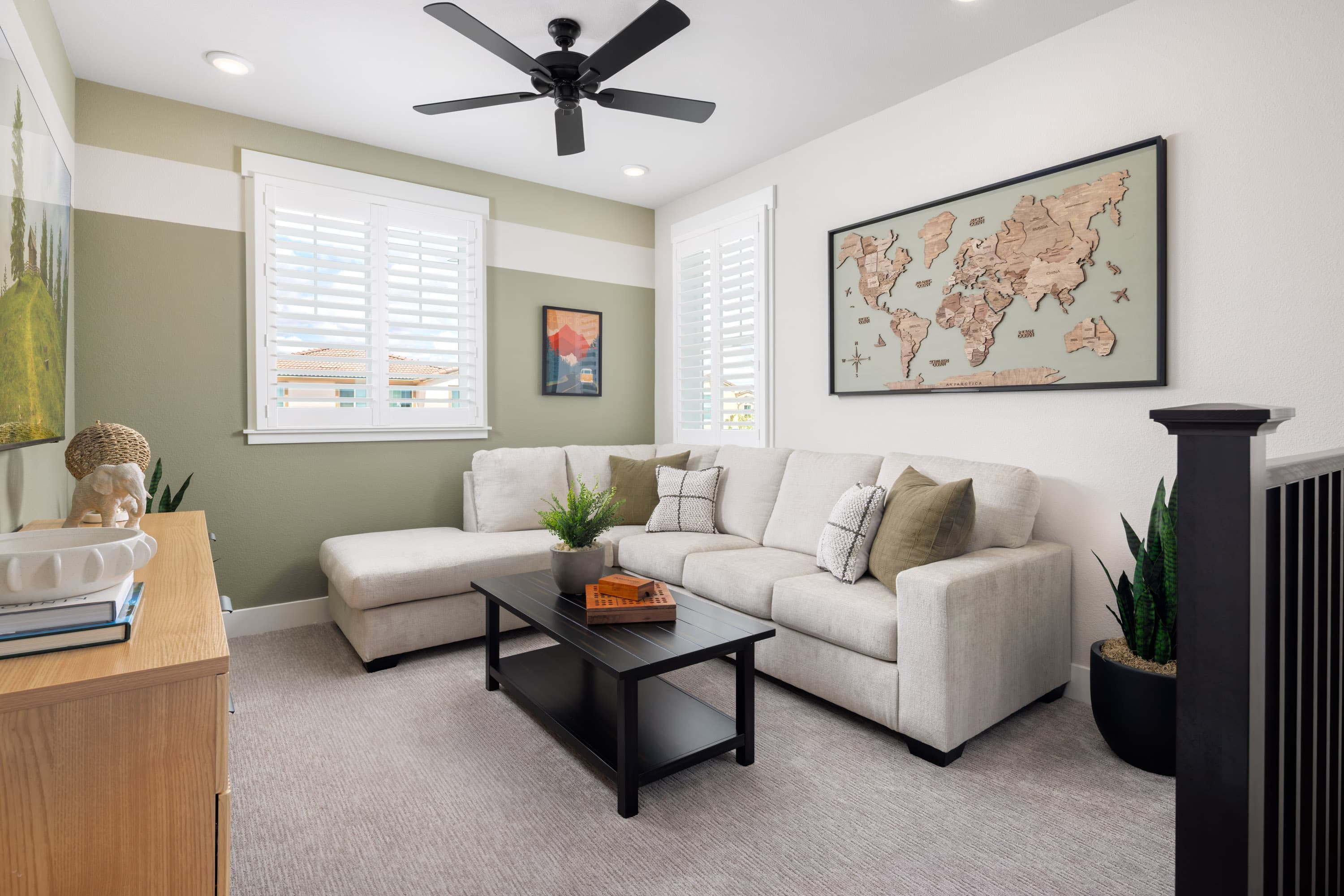 loft with gray carpet, green wall, tan sofa, and black coffee table
