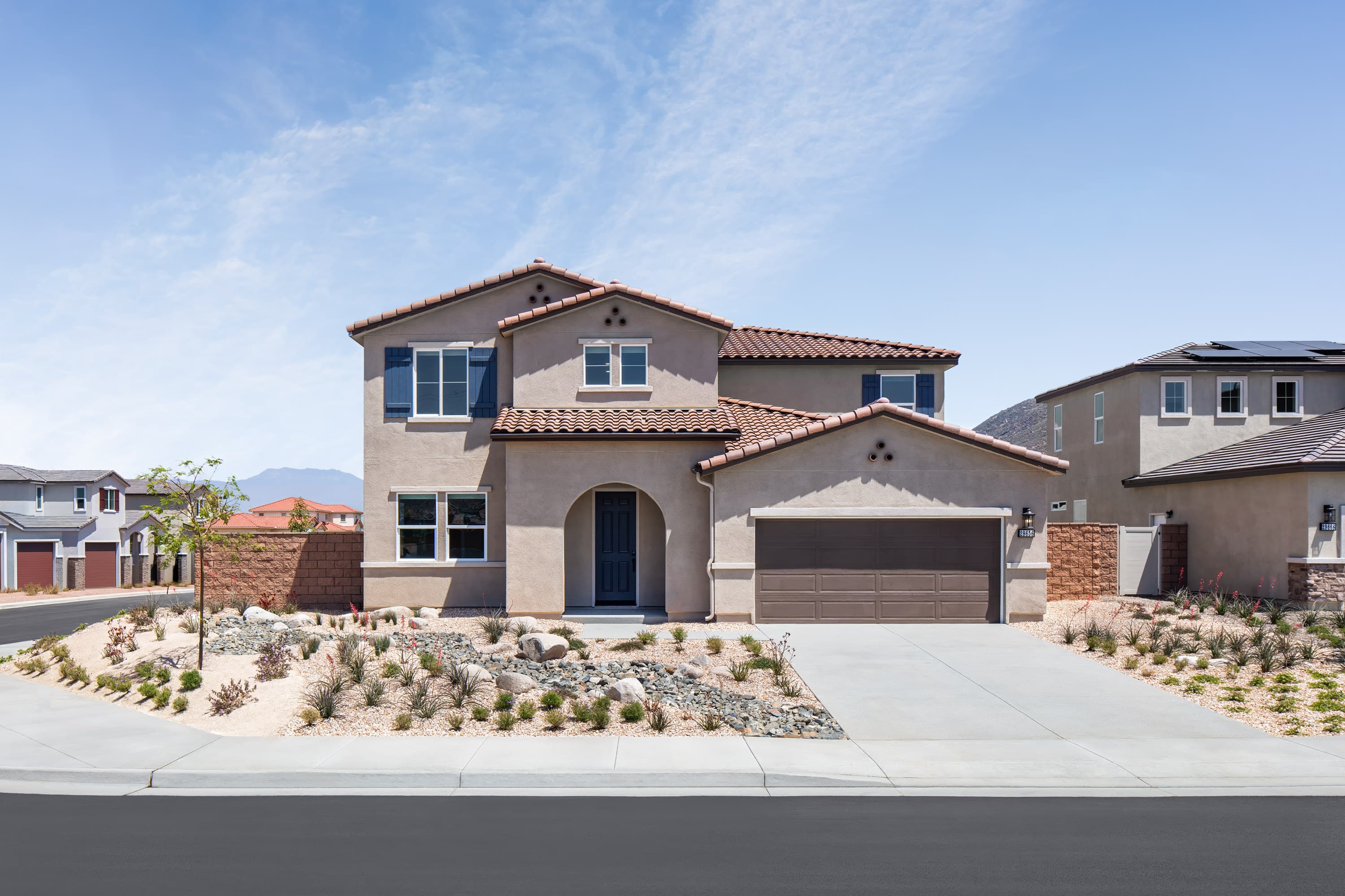 exterior of two-story home with desert landscaping and neutral paint