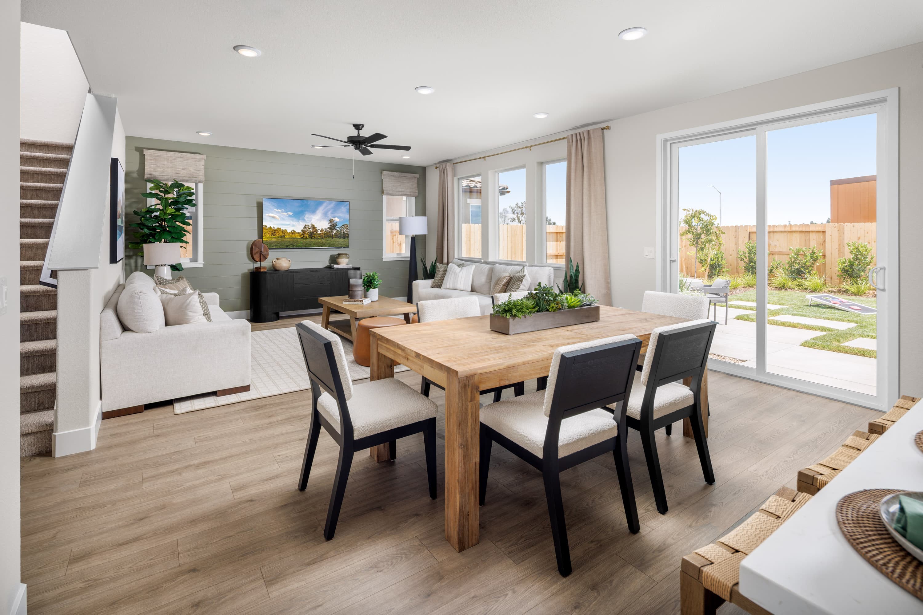 dining room with wood floors, wood table with six black & white chairs, and sliding glass door to the backyard