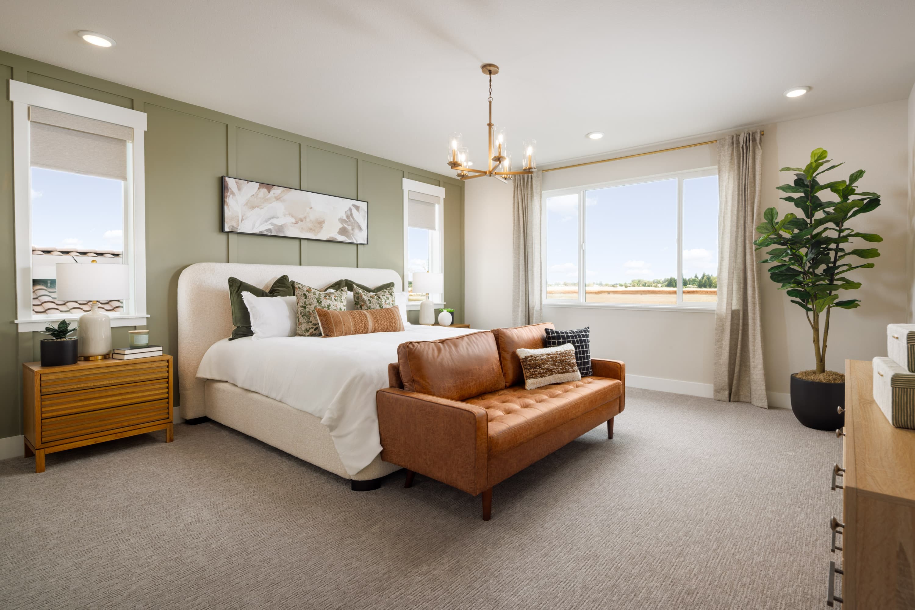 bedroom with three windows, gray carpet, green wall behind white bed, and brown leather sofa at foot of bed