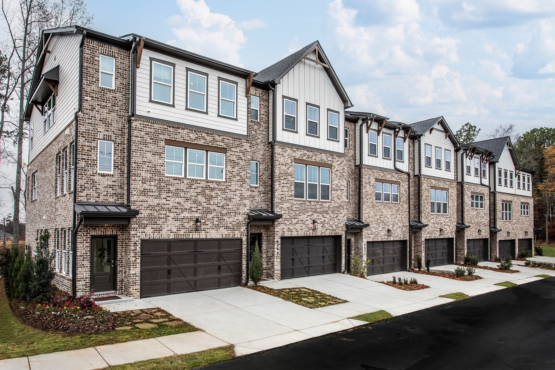 front of townhome building with brick and dark garage doors
