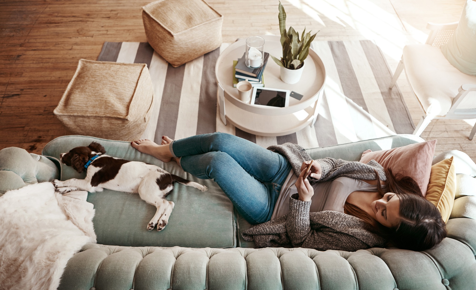 woman laying on couch with dog looking for homes on her phone